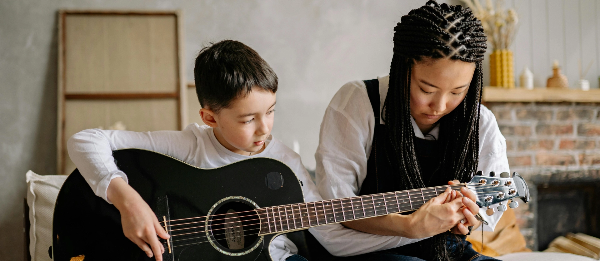 A young boy and his mother playing guitar.