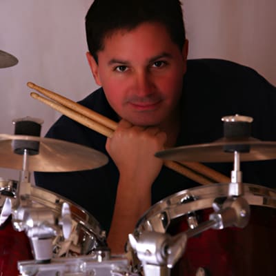 Drummer posing behind red drum kit