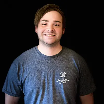 A man in a blue shirt smiling for the camera.