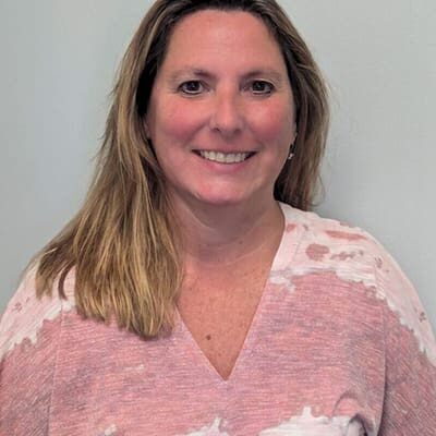 A woman in pink shirt smiling for the camera.